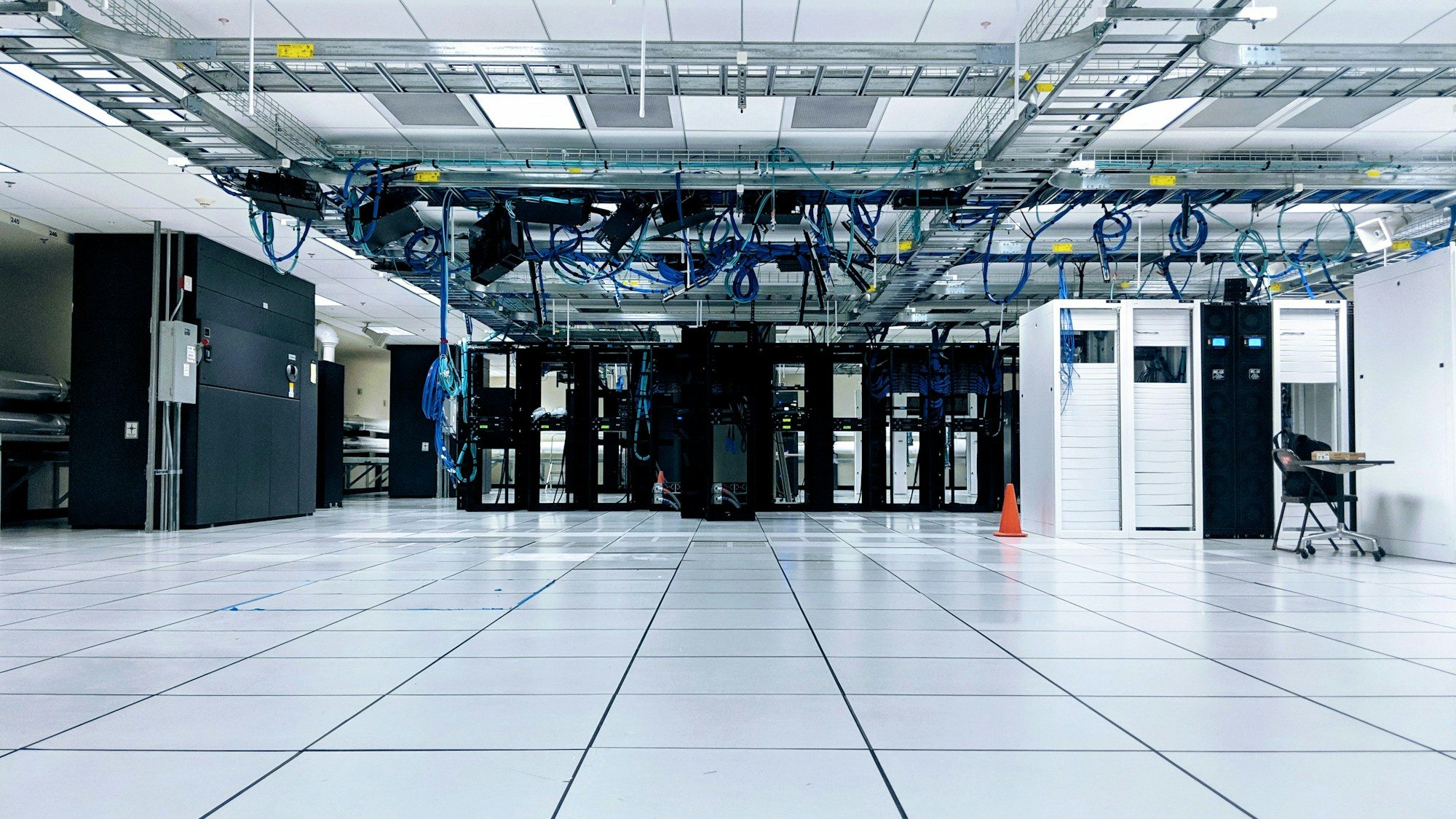 Server hall with black and white network cabinets and overhead blue cabling